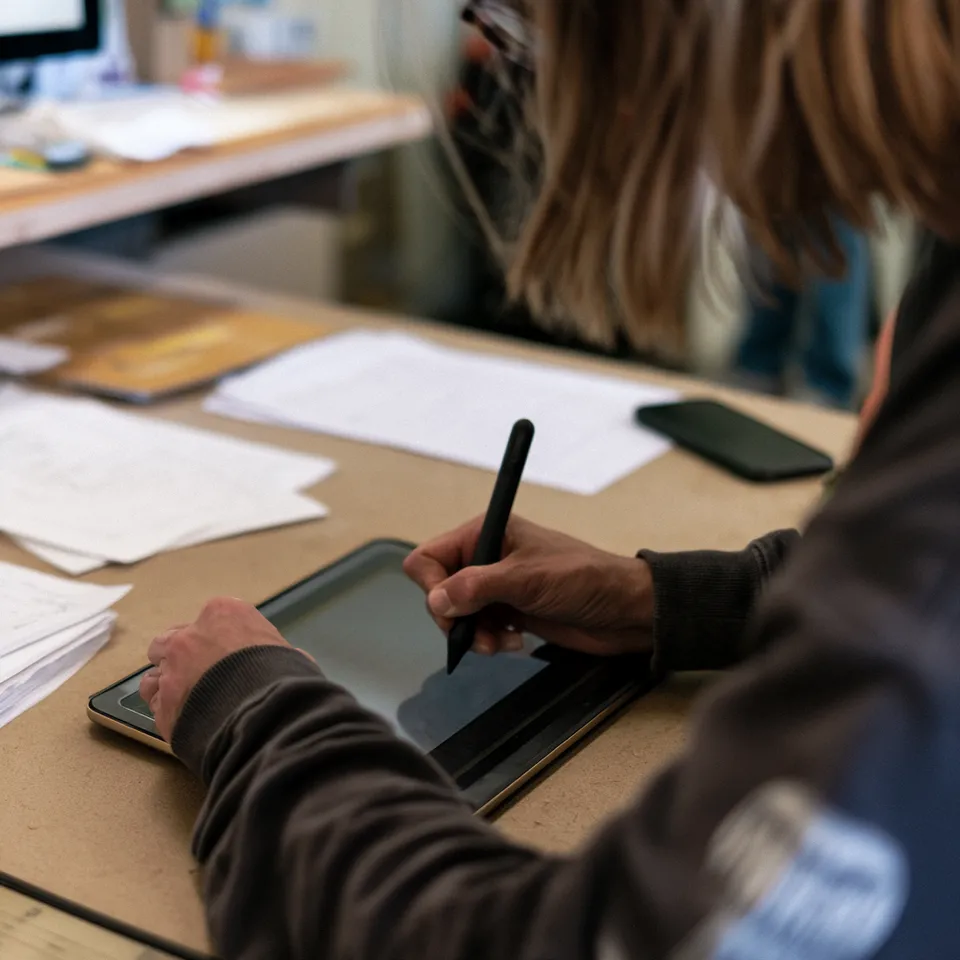 A person signing on a tablet with a stylus at a desk
