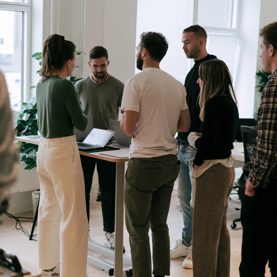 A small team standing around a high table for a morning stand-up
