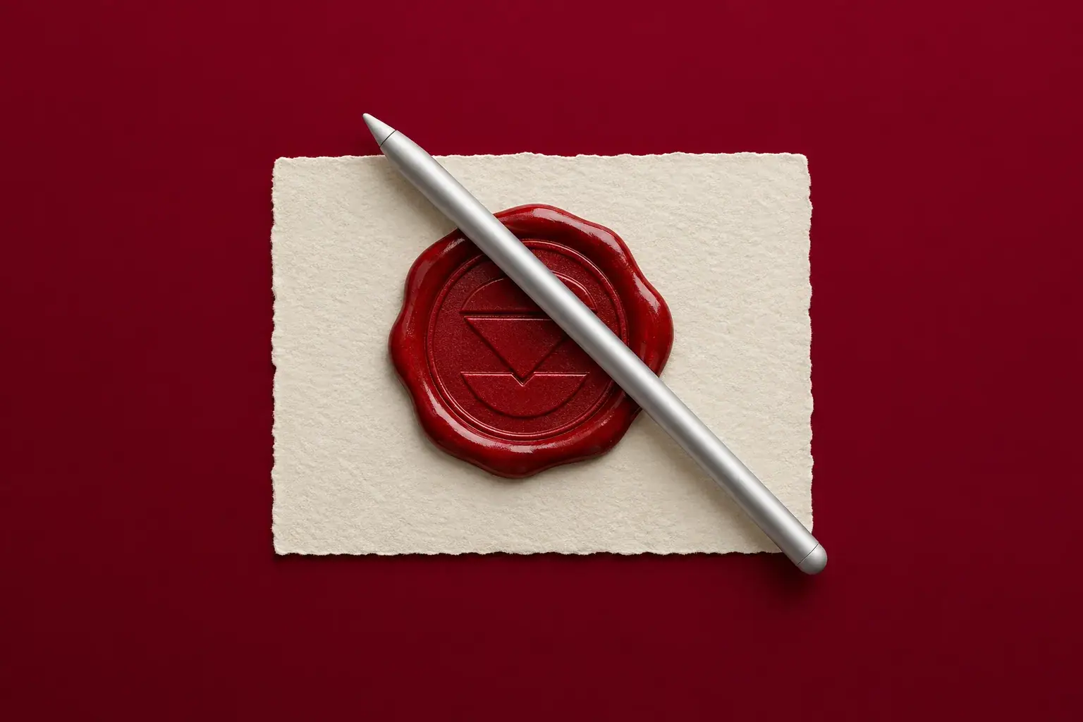 A red wax seal on cream paper with a tablet stylus lying across it